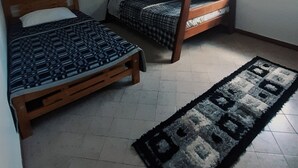 A small, compact room with two bunk beds, a single bed, a window with blinds, and a patterned rug on the floor. - Casa Dalima, home between mountains (Villa de leyva)