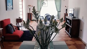 A living room with a dining table, red sofa, and a vase of flowers. - Casa Dalima, home between mountains (Villa de leyva)