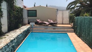 A swimming pool with lounge chairs, a small building, and a stone wall. - Casitas Las Pereras (Los Llanos de Aridane)