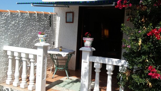 A balcony with a white railing, a small table, and potted plants. - Casitas Las Pereras (Los Llanos de Aridane)