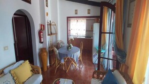 A cozy living room with a dining area, a kitchen, and a large window with curtains. - Casitas Las Pereras (Los Llanos de Aridane)