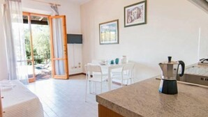 Una cocina luminosa con una cafetera en la encimera, una mesa de comedor con sillas y un ventanal corredero que da a un espacio exterior.