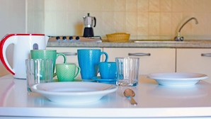 Una encimera de cocina con diferentes tazas, una cafetera y una cuchara.
