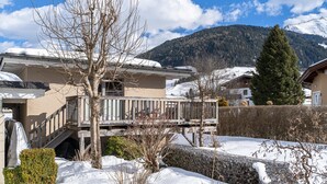 A residential area with a house featuring a balcony, a stone wall, and a snow-covered landscape with mountains in the background. - Detached holiday home in centre of Mittersill (Mittersill)