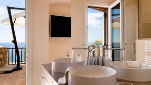 A modern bathroom with two large round sinks, a mirror, and a TV mounted on the wall. - Luxurious apartment "Piccolo Pevero retreat" with sea view, balcony and terrace (Porto Cervo)