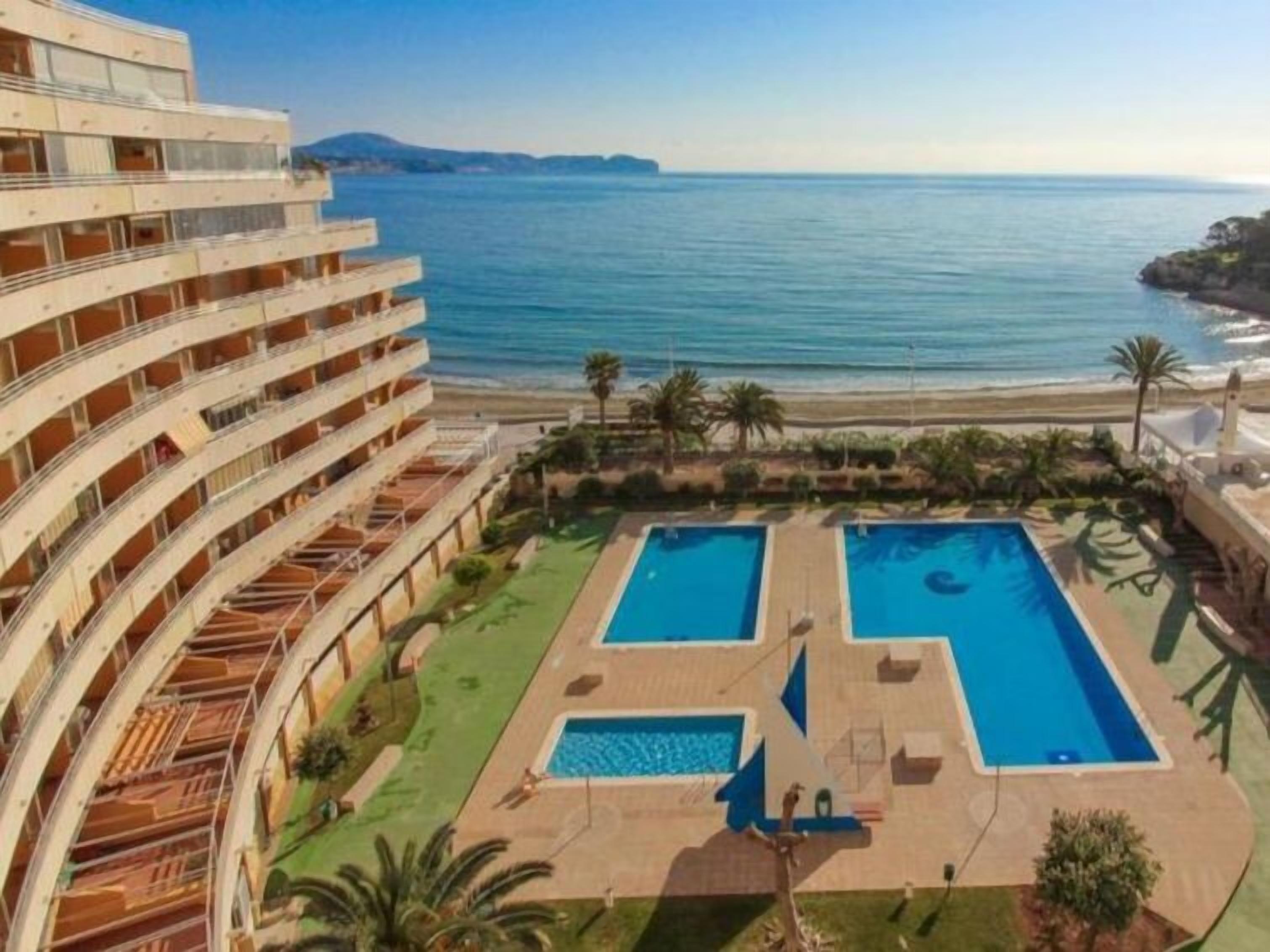 A hotel with a pool area, a beach view, and a multi-story building.