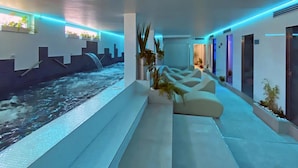 Un área de piscina interior moderna con fuente, asientos e iluminación ambiental.