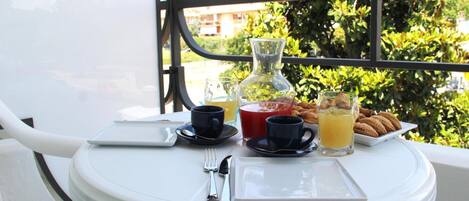 A table set for breakfast with a beverage pitcher, cups, and pastries.