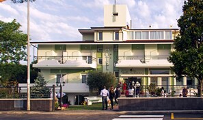 Un hotel con fachada verde, varios balcones y un letrero que indica que es un hotel.