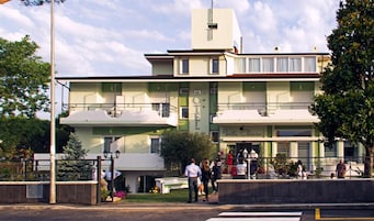 Un hotel con fachada verde, varios balcones y un letrero que indica que es un hotel.