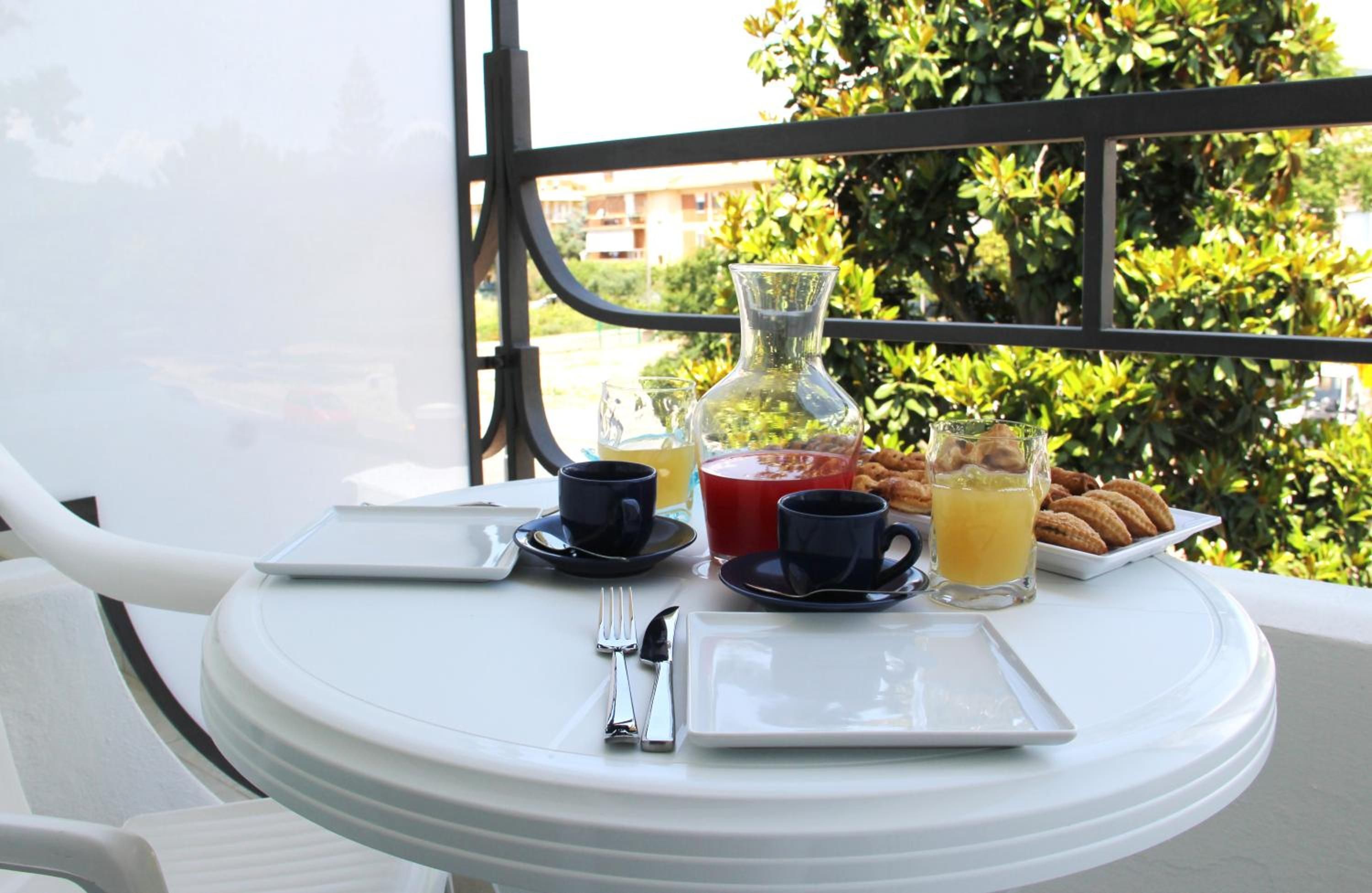A table set for breakfast with a beverage pitcher, cups, and pastries.