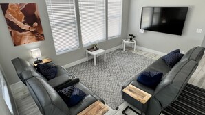 A modern living room with two grey sofas, a coffee table, and a TV mounted on the wall. - Lake View Modern House with Beautiful Sunsets! (Page)