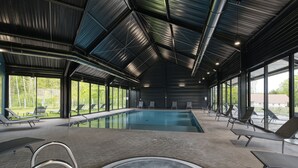 Ein Hallenbad mit Liegestühlen und einem Whirlpool.