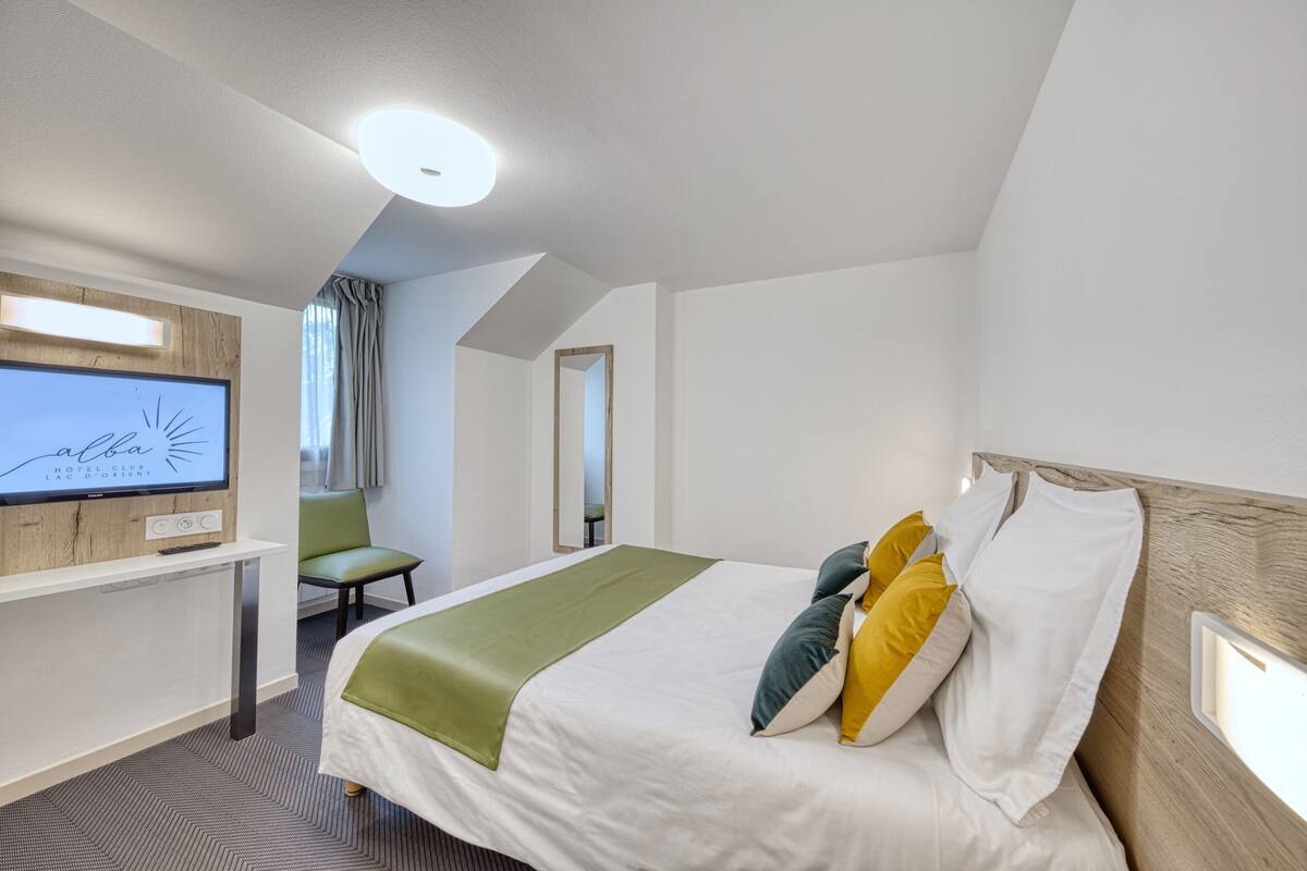 A hotel room with a bed, a TV, a desk, and a chair.