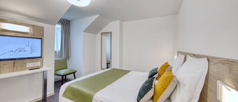 A hotel room with a bed, a TV, a desk, and a chair.