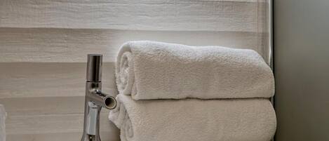 A bathroom with a round mirror, a sink, and a towel.