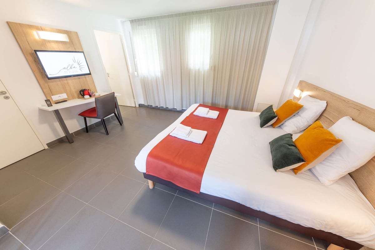 A hotel room with a bed, a desk, and a TV.