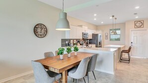 Une cuisine moderne avec des meubles blancs, une table à manger en bois et un îlot central.