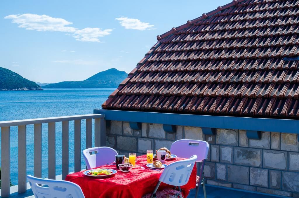 Een terras met een ontbijttafel met uitzicht op een waterpartij en heuvels.