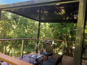 An outdoor patio with a grill, seating, and a view of dense foliage. - Fernbrook Escape Secluded and Serene (Cockatoo)