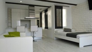 A modern bedroom with a bed, a white sofa, a chair, and a large mirror. - Atico de Lujo (Guia de Isora)