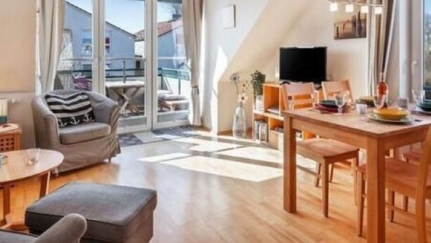 A modern living room with a dining area, large windows, and a view of the outside. - Waldstr. 34 Wo.05 - Wo.05 (Kühlungsborn)