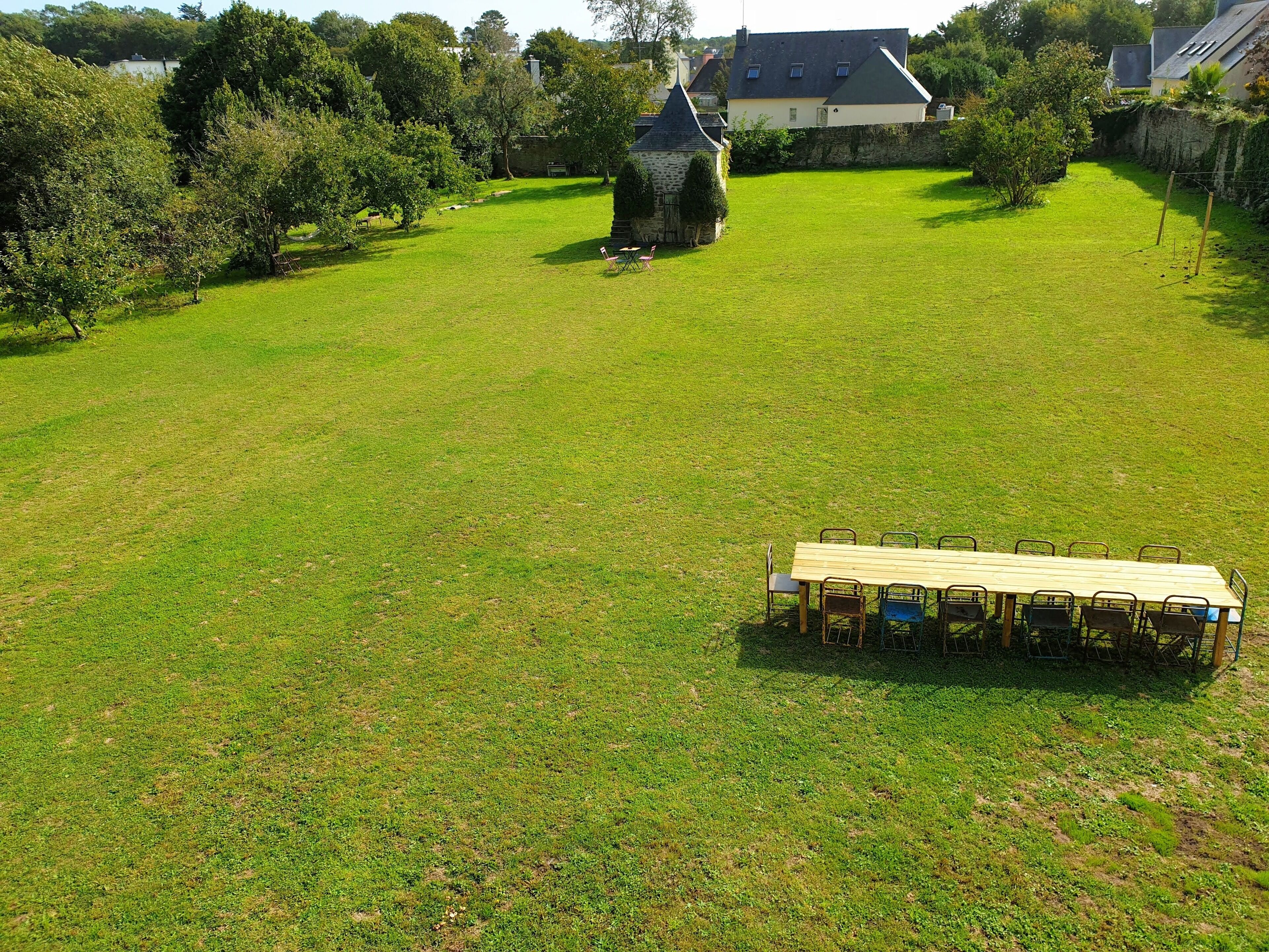A spacious grassy area with a stone structure and a long table with chairs.
