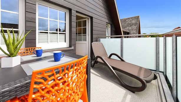 A modern outdoor seating area with a table, chairs, and a potted plant. - Ferienwohnung Juist - Ferienwohnungen Min Huus (Neuharlingersiel)