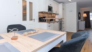 A modern kitchen with white cabinets, a wooden countertop, and a built-in microwave. - Ferienwohnung Juist - Ferienwohnungen Min Huus (Neuharlingersiel)