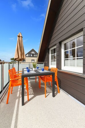 A balcony with a table and chairs, a potted plant, and a window.