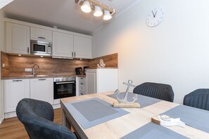A modern kitchen with white cabinets, a wooden backsplash, and a dining area with a table set for four.