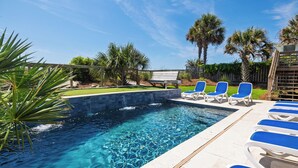 A swimming pool with clear blue water, surrounded by a tiled deck and blue lounge chairs. - Exquisite Oceanfront Oasis: Immerse in Luxury with Pool & Putting Green at this (Folly Beach)