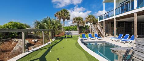 A pool area with a golf cart, lounge chairs, and a building with a balcony.