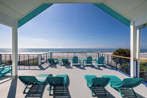 A covered outdoor seating area with chairs and tables, overlooking a beach. - Exquisite Oceanfront Oasis: Immerse in Luxury with Pool & Putting Green! (Folly Beach)