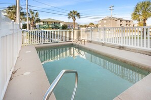 A swimming pool with a white fence and a metal ladder, surrounded by a residential area with houses and palm trees. - Amazing salt marsh views, large villa w/game room & private pool, large covered porches (North Myrtle Beach)