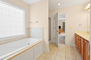 A bathroom with a bathtub, a vanity with a sink, and a window.