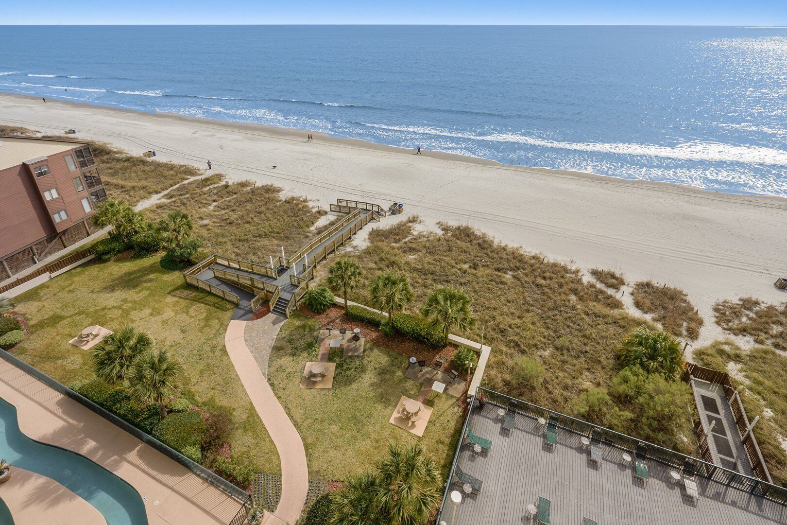 A beachfront hotel with a patio area, a pool, and a view of the ocean.