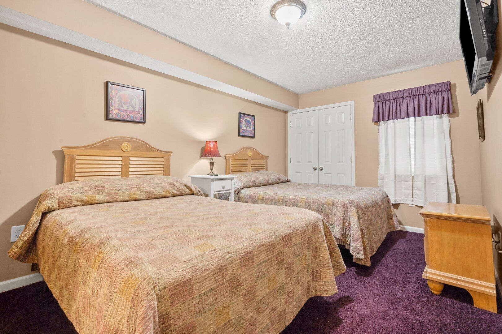 Un dormitorio con dos camas, una mesita de noche, un aparador y una lámpara de techo.
