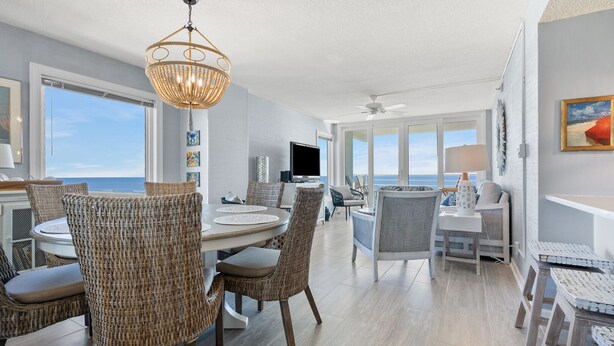 A spacious dining area with wicker chairs and a central table, overlooking a scenic ocean view. - Direct ocean front condo with stunning renovations & updated "coastal chic" decor! (North Myrtle Beach)