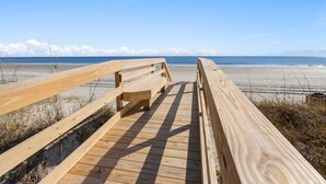 A wooden boardwalk leading to a beach with a clear view of the ocean and distant mountains. - Direct ocean front condo with stunning renovations & updated "coastal chic" decor! (North Myrtle Beach)