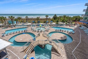 Un espace piscine comprenant plusieurs piscines, des chaises longues et une vue sur la plage.