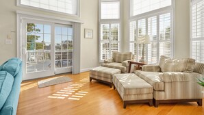 A spacious living room with large windows, a sliding glass door leading to an outdoor area, and a comfortable seating arrangement. - Elegant, Luxury Home w/Private Pool & Easy Beach Access-North Myrtle Beach Rental (North Myrtle Beach)