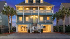 A two-story house with a balcony, a staircase, and a porch. - Luxurious oceanfront home with private pool, putting green, private beach access and more (North Myrtle Beach)