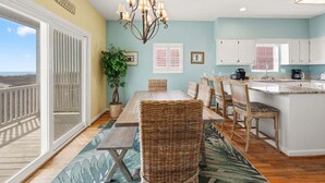 A dining area with a table, chairs, a chandelier, and a view of the beach. - Luxurious oceanfront home with private pool, putting green, private beach access and more (North Myrtle Beach)