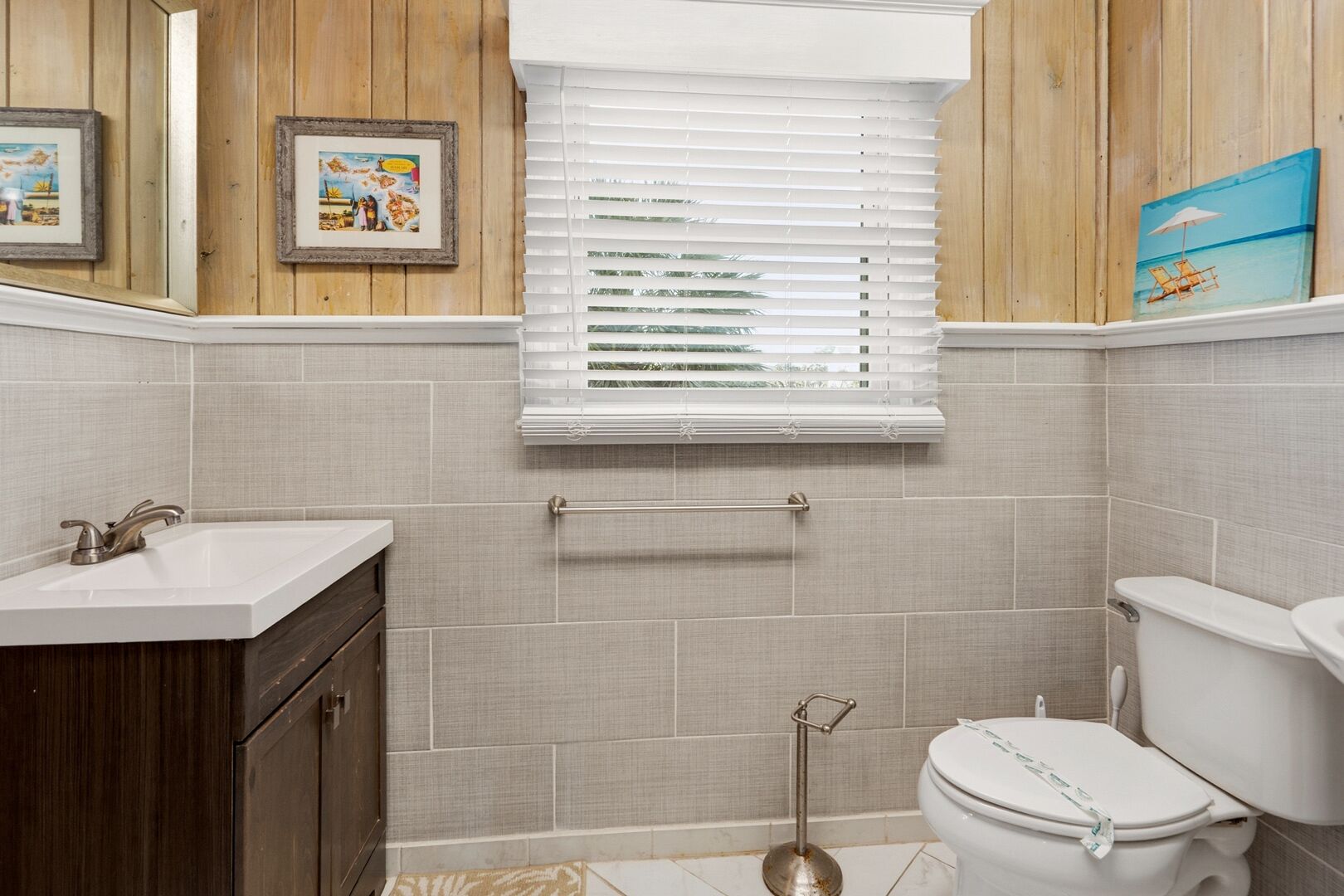 A bathroom with a sink, toilet, and window blinds.