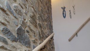 Una pared de piedra con barandilla de madera y una escalera de mármol.