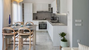 Una cocina moderna con armarios blancos, un comedor con sillas de madera y una pequeña planta en maceta.