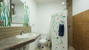 Un baño con lavamanos de granito, inodoro blanco y ducha con una toalla colgada en la pared.