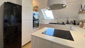 A modern kitchen with a black refrigerator, built-in oven, and a large island with an induction cooktop.