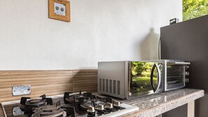Une cuisine équipée d’une cuisinière à gaz, d’un four à micro-ondes et d’un four grille-pain, le tout installé sur un plan de travail en granit.